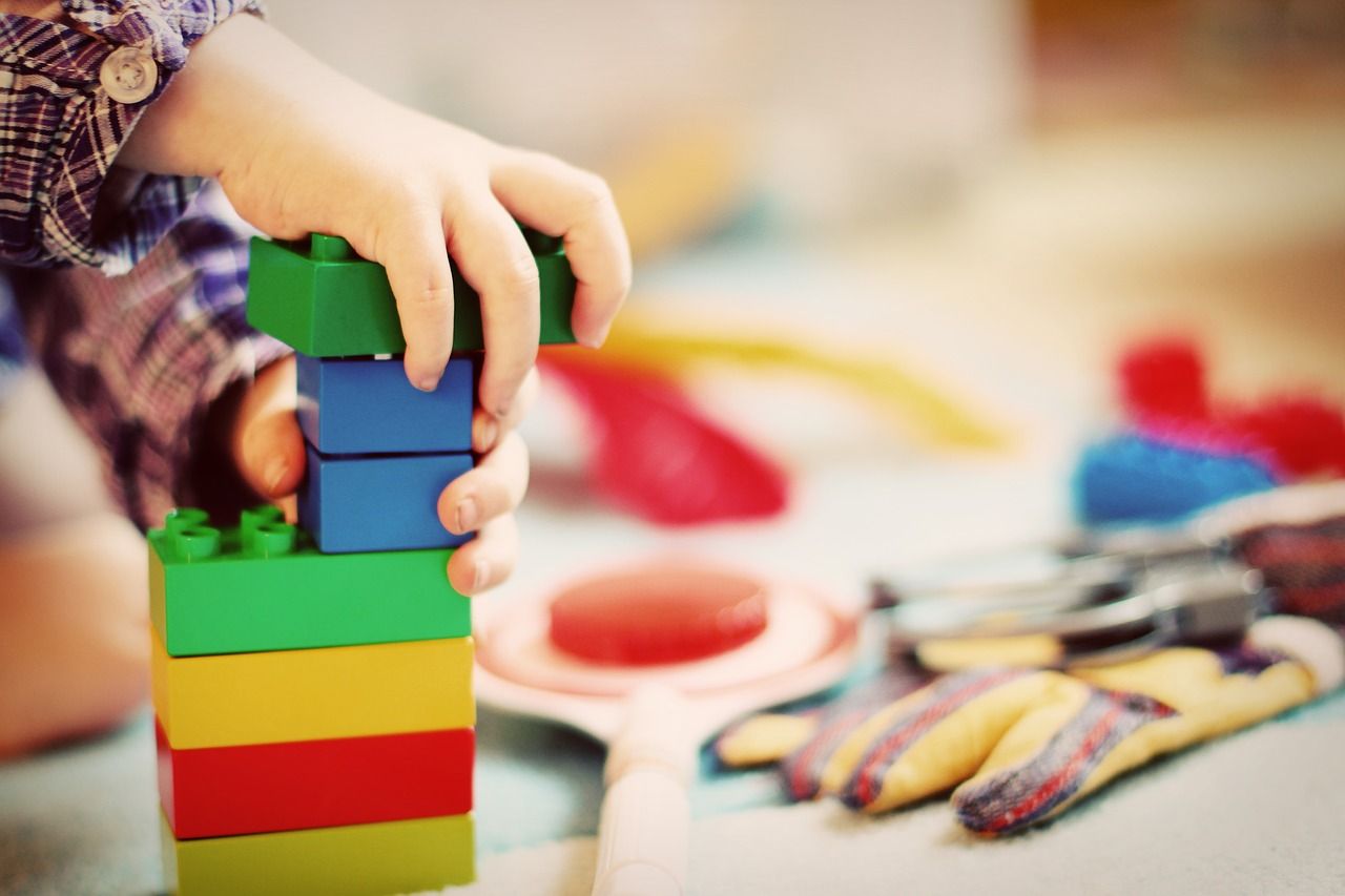 A child's hand stacking colourful building blocks
