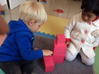 Two children building with the pink tower