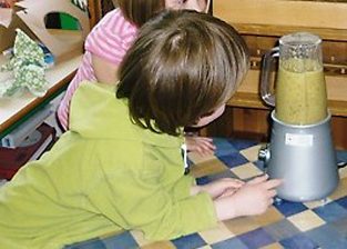 A child making a smoothie with a blender