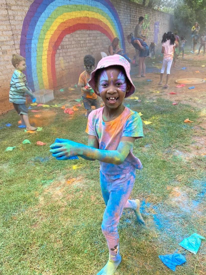 A girl with a butterfly face paint laughing on colour day
