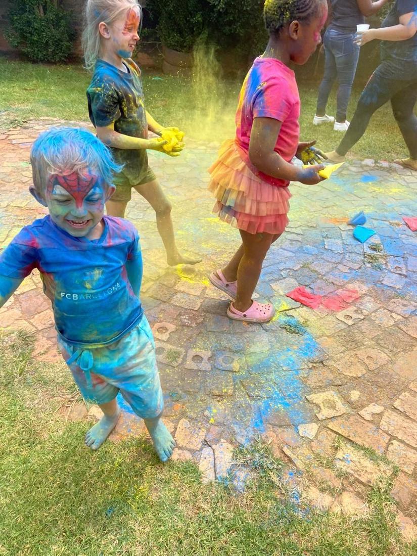 Children running through clouds of coloured powder on colour day