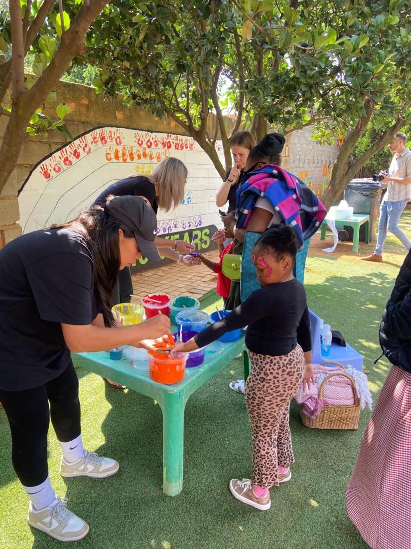 A girl dipping her hand in paint for the handprint wall