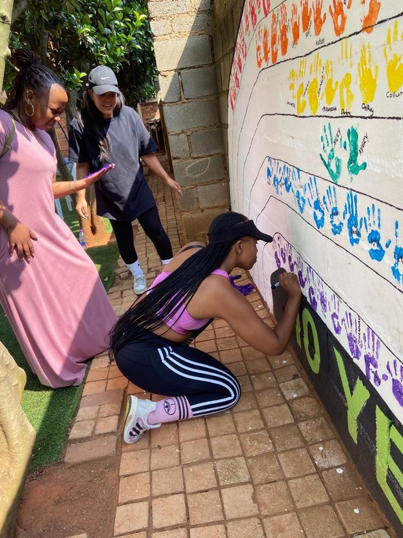 Parents adding names to the children's handprint mural
