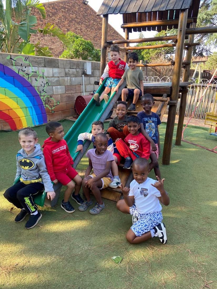 A big group of children posing on the jungle gym and slide