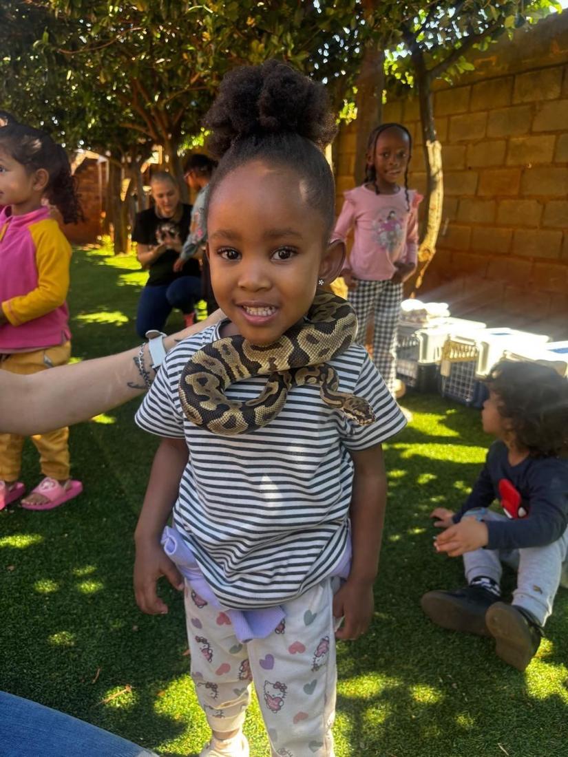 A smiling girl with a python draped around her shoulders